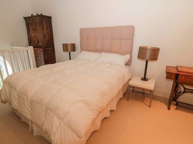 A bedroom with a bed with a tufted headboard two bedside tables with lamps a wooden wardrobe and a sewing machine table at 2 The Reformed Church Embleton