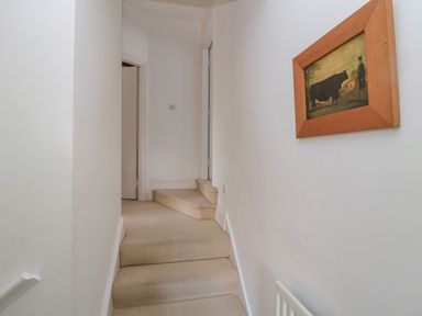A narrow hallway with carpeted stairs and a framed picture on the wall at 2 The Reformed Church in Embleton