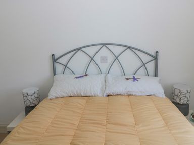 A bed with a metal headboard with two white pillows with small decorations and a beige comforter at 2 The Reformed Church Embleton