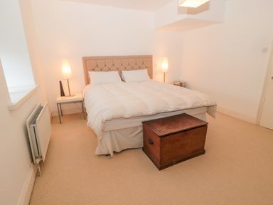 A bedroom with a double bed two bedside tables with lamps a wooden chest at The Reformed Church in Embleton
