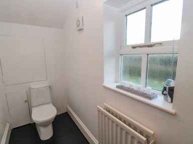 A small bathroom with a toilet radiator and window with candles and radio on sill at 2 The Reformed Church in Embleton