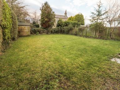 A backyard with grass lawn wooden shed and wooden fence at 2 The Reformed Church in Embleton