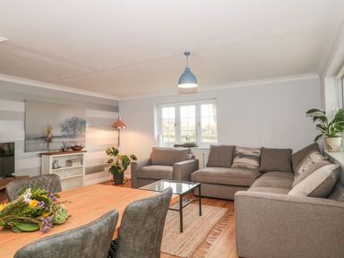 A living room with a gray sofa set a wooden dining table with chairs and plants at Rainbow View in Churchstanton near Churchinford
