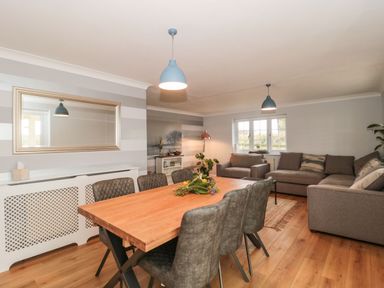 A dining and living room with a wooden table and grey chairs and sofas at Rainbow View in Churchstanton near Churchinford