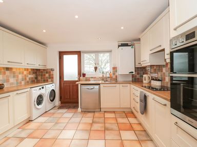 A kitchen with white cabinets appliances and a wooden door at Rainbow View in Churchstanton near Churchinford