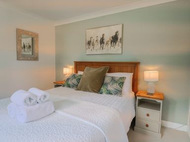 A bedroom with a bed, nightstand, and wall art at Rainbow View in Churchstanton near Churchinford
