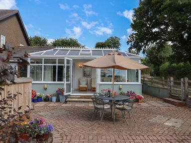 A garden with a table and chairs under an umbrella at Rainbow View in Churchstanton near Churchinford
