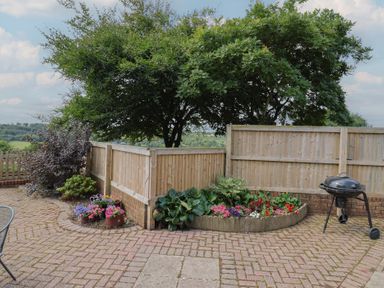 A garden with flowers and a grill at Rainbow View in Churchstanton near Churchinford