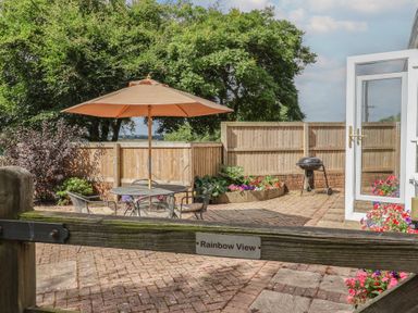A garden with a seating area and umbrella at Rainbow View Churchstanton near Churchinford