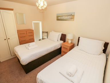 A bedroom with two single beds a wooden wardrobe a chest of drawers and a bedside table with a lamp at The Old Farm House in Redberth near Pentlepoir