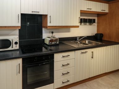 A kitchen with a microwave toaster kettle sink and cabinets at The Old Farm House in Redberth near Pentlepoir