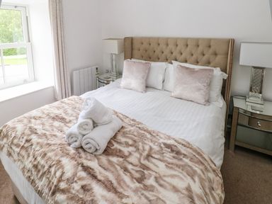 A bedroom with a bed with pillows and rolled towels on a fur blanket at The Old Farm House in Redberth near Pentlepoir