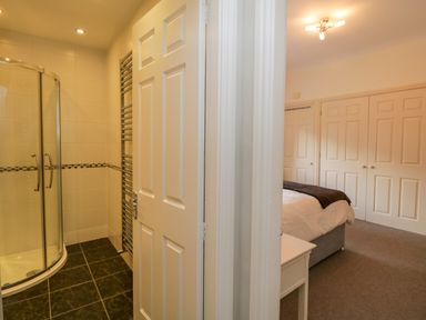 A bathroom with a corner shower and a bedroom with a bed and wardrobes at Lake House Loft in Bowness-On-Windermere