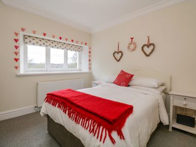 A bedroom with a bed a red throw and heart decorations on the wall at Lake House Loft in Bowness-On-Windermere