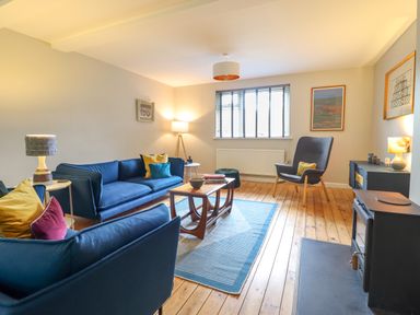 A living room with blue sofas armchair wooden coffee table and floor lamp at The Wardens House in Tregynon near Newtown