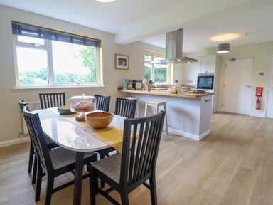A kitchen and dining area with a table, chairs, stools, and kitchen island at The Wardens House in Tregynon near Newtown