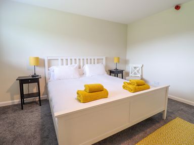 A bedroom with a white bed and yellow towels on the bed with side tables and lamps at The Wardens House in Tregynon near Newtown