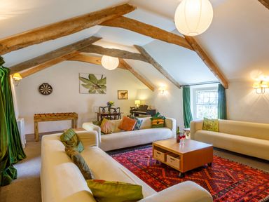 A sitting room with wooden beams foosball table and sofas at Aarons Cottage in St Teath