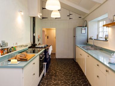 A kitchen with a stove oven cutting board bread and butter on the counter at Aarons Cottage in St Teath