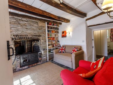 A living room with stone fireplace sofas and a bookshelf at Aarons Cottage in St Teath