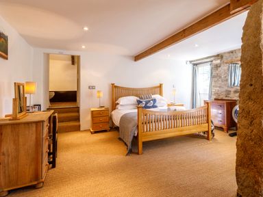 A bedroom with a wooden bed two bedside tables a dresser and a window at Aarons Cottage in St Teath