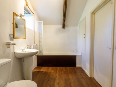 A bathroom with a bathtub sink toilet wooden floor and white walls at Aarons Cottage in St Teath