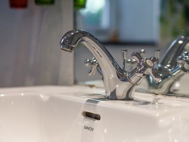 A close up of a silver faucet on a white sink with a mirror reflection at Aarons Cottage in St Teath