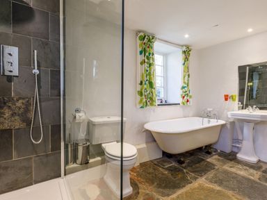 A bathroom with a clawfoot bathtub a toilet a shower with a glass door and a pedestal sink at Aarons Cottage in St Teath