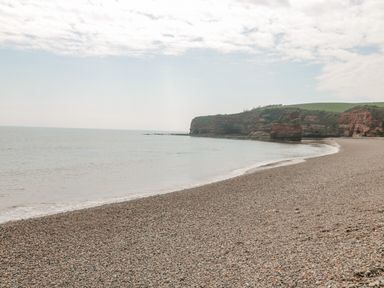 A pebble beach with cliffs and calm sea at The Retreat in Otterton