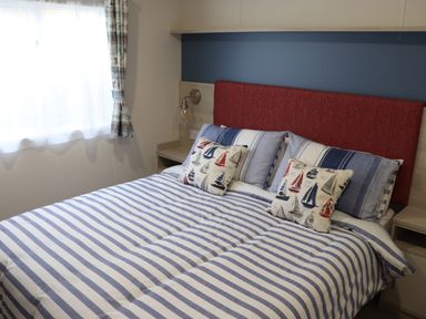 A bedroom with a bed with striped bedding and sailboat patterned pillows at The Retreat in Otterton
