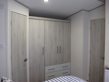 A bedroom with a wardrobe and two doors with light wood finish at The Retreat in Otterton