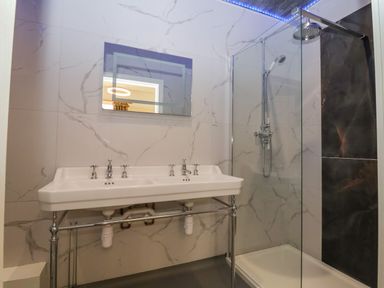 A bathroom with a double sink and a shower area with glass partition at The Lloyd George in Bontnewydd Gwynedd