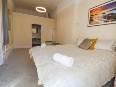A bedroom with a bed with pillows and rolled towels a doorway to a bathroom and a standing mirror at The Lloyd George in Bontnewydd Gwynedd