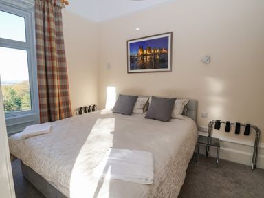 A bedroom with a bed pillows folded towels window with curtains and a framed picture on the wall at The Lloyd George in Bontnewydd Gwynedd