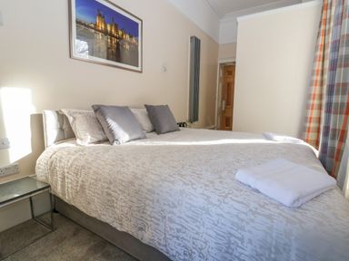 A bedroom with a large bed pillows folded towels wall art and a wooden door at The Lloyd George in Bontnewydd Gwynedd