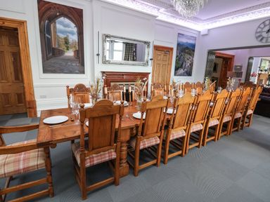 A dining room with a long wooden table and many chairs in a house at The Lloyd George in Bontnewydd Gwynedd