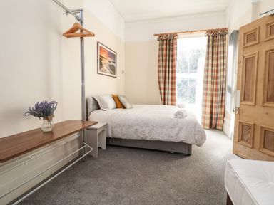 A bedroom with a bed pillows rolled towels a window with plaid curtains and a wooden door at The Lloyd George in Bontnewydd Gwynedd