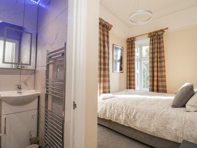 A bedroom with a bed next to a window and an en suite bathroom with a sink and heated towel rail at The Lloyd George in Bontnewydd Gwynedd