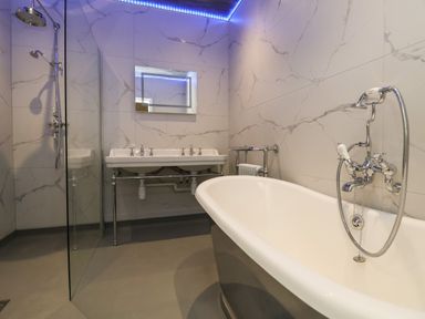 A bathroom with a freestanding bathtub shower area and double sinks at The Lloyd George in Bontnewydd Gwynedd