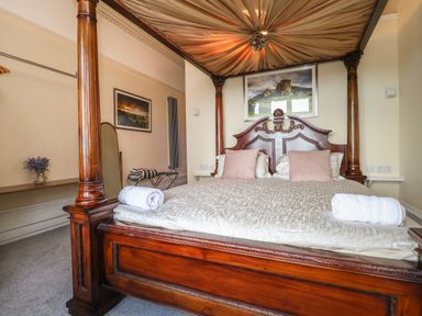 A bedroom with a wooden four poster bed with beige bedding and towels at The Lloyd George in Bontnewydd Gwynedd
