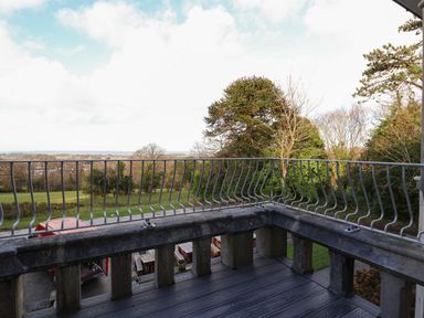 A balcony with a metal railing overlooking trees and fields at The Lloyd George in Bontnewydd Gwynedd