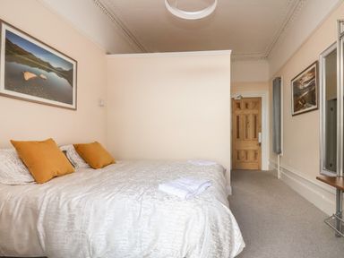 A bedroom with a double bed with pillows and towels a wooden door and framed pictures on the walls at The Lloyd George in Bontnewydd Gwynedd
