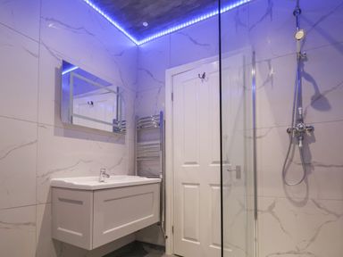 A bathroom with a sink cabinet mirror door shower and towel rail at The Lloyd George in Bontnewydd Gwynedd