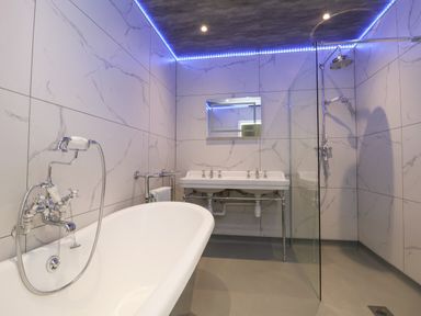 A bathroom with a bathtub sink shower and wall tiles at The Lloyd George in Bontnewydd Gwynedd
