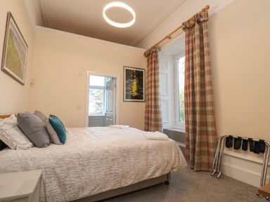A bedroom with a double bed pillows curtains and a door at The Lloyd George in Bontnewydd Gwynedd