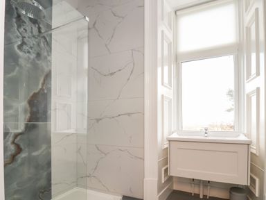 A bathroom with a shower area and a sink under a window at The Lloyd George in Bontnewydd Gwynedd