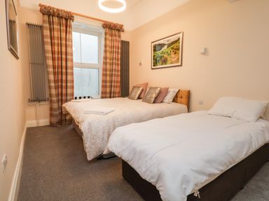 A bedroom with two beds plaid curtains and a framed landscape picture on the wall at The Lloyd George in Bontnewydd Gwynedd