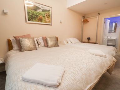 A bedroom with two beds decorative pillows towels and a clothing rack with hangers at The Lloyd George in Bontnewydd Gwynedd
