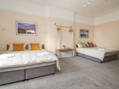 A bedroom with two double beds pillows and folded towels on a carpeted floor at The Lloyd George in Bontnewydd Gwynedd