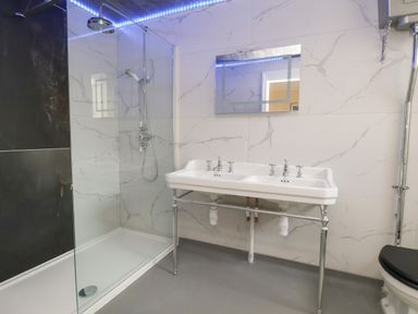 A bathroom with a dual sink, a shower area with glass partition, and a toilet at The Lloyd George in Bontnewydd Gwynedd